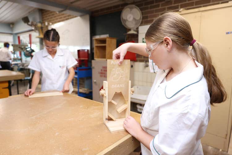Two students working on a wood project at a wooden work bench
