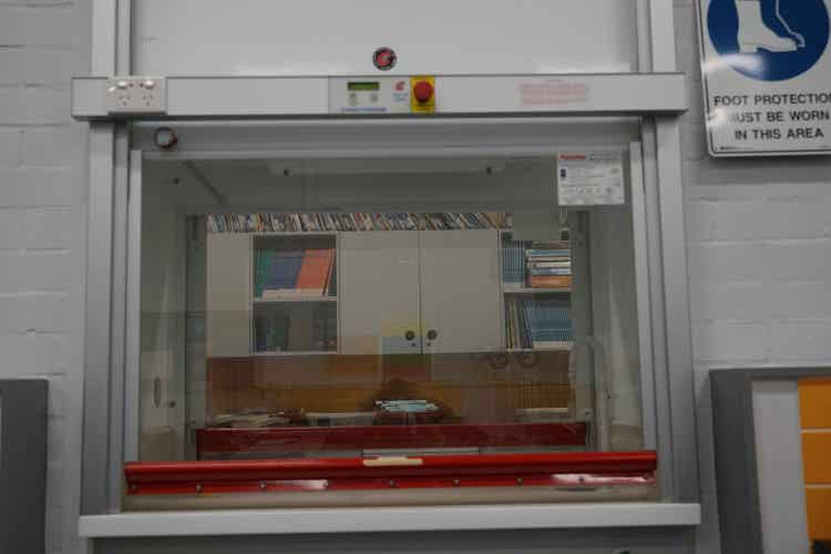 A two way chemical fume cupboard with safety glass on both sides and an emergency off button at the top.