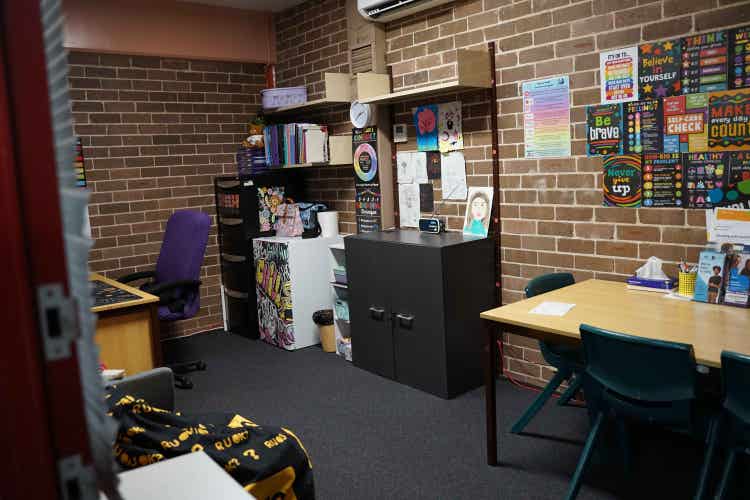 An office space with a table and chairs, a bean bag, cupboards, and a desk with an office chair in the background.