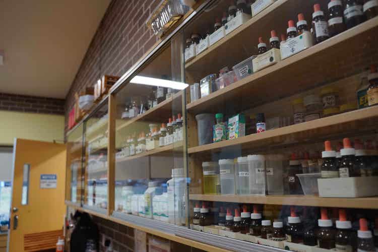 Various chemicals stored in a glass-fronted cupboard.