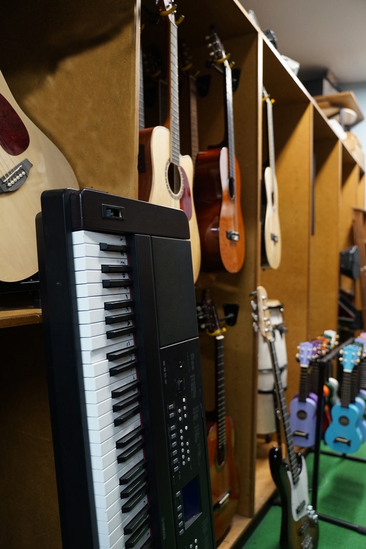 Various musical instruments in a store room, including guitars, a keyboard, and a ukulele.